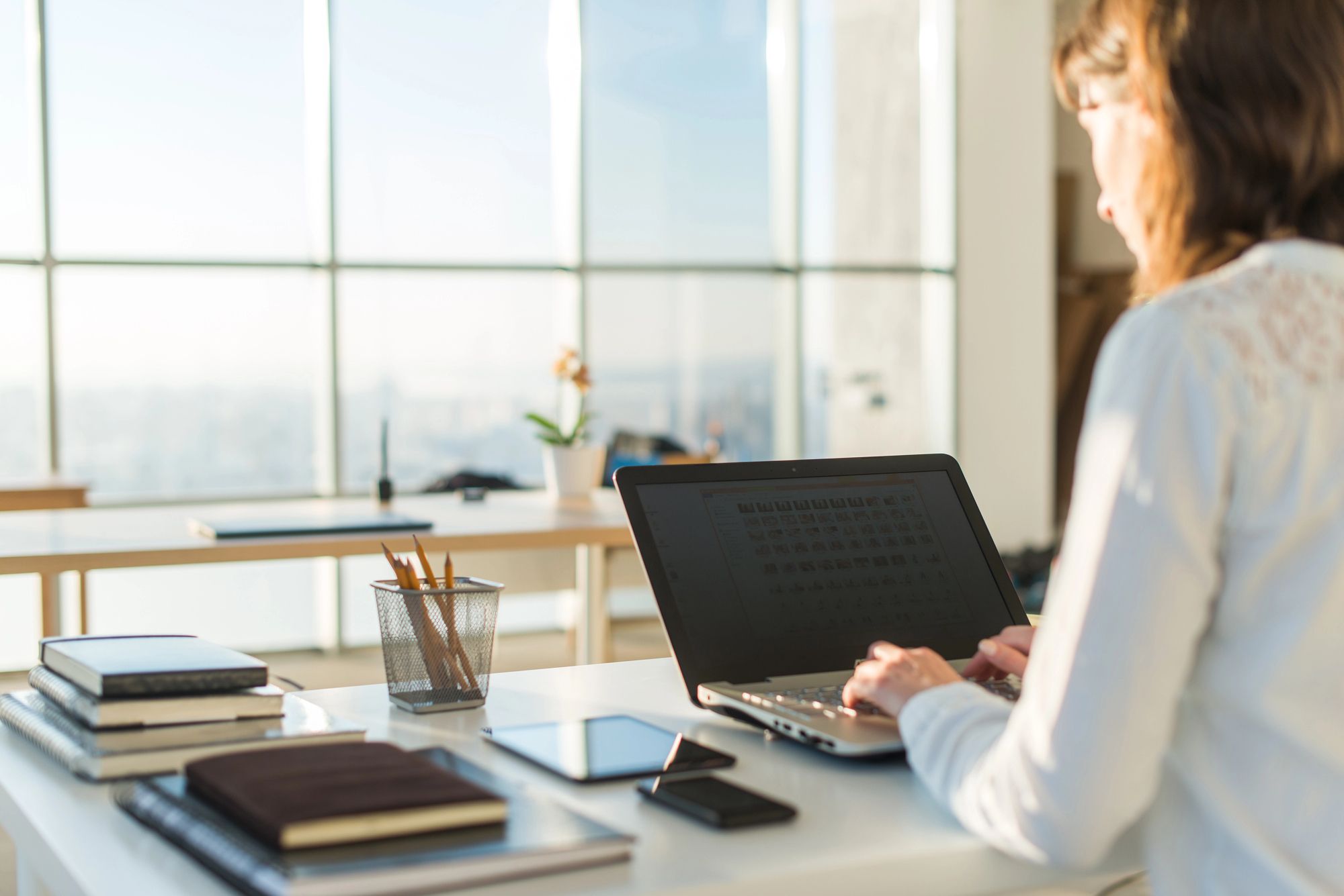 Designer working on a laptop at a desk overlooking the city