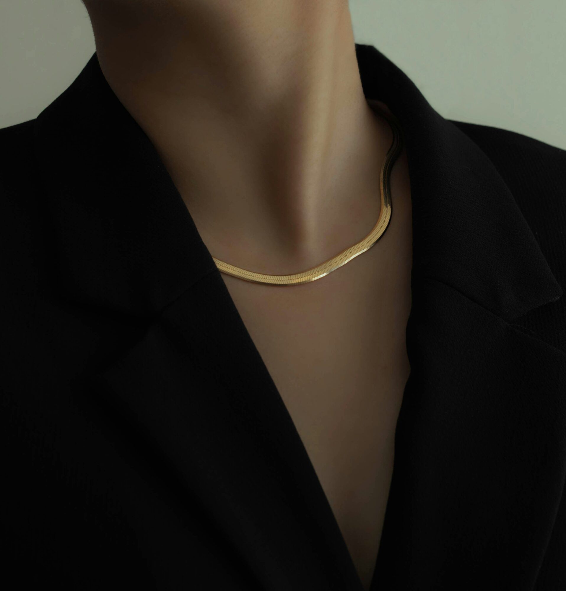 Gold herringbone chain necklace worn with a black blazer